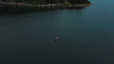 Drone-aerial-view-of-a-man-on-a-boat-in-lake-Atitlan,-Guatemala