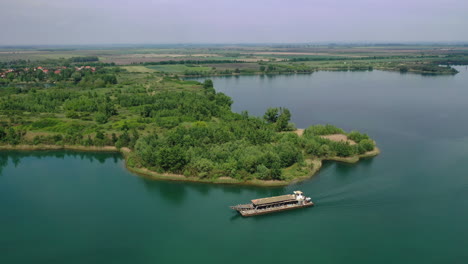 Barco-Industrial-Navegando-Lentamente-A-Lo-Largo-Del-Río-Con-árboles-En-El-Paseo-Marítimo