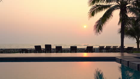 Ruhe-über-Tropischem-Meer-Und-Luxuriösem-Pool-Mit-Sonnenuntergangssonne,-Palme-Und-Ruhigem-Wasser,-Vollbild