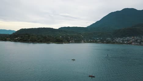 Local-fisherman-boats-in-Lake-Atitlan,-Guatemala---Drone-aerial-landscape-view-of-mountains-and-volcanoes