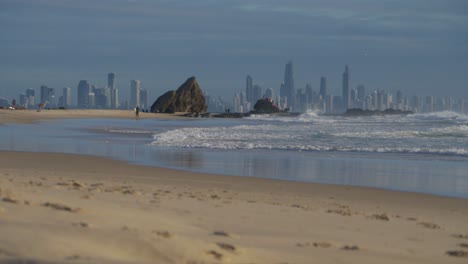 Ocean-Waves-At-Beach-And-Currumbin-Rocks---Surfers-Paradise-Skyline-In-The-Background---Currumbin-Alley-In-Gold-Coast,-Queensland,-Australia