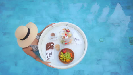 Top-view-of-sexy-woman-with-hat-holding-floating-exotic-breakfast
