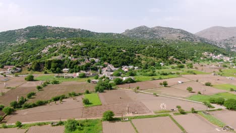 Aerial-approach-of-village-surrounded-by-unspoiled-nature,-Spinalonga