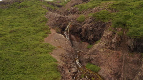 Small-waterfall-in-Iceland's-westfjords,-drone-shot