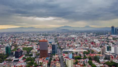 City-drone-shot-with-a-cloudy-sky-and-2-volcanoes-on-the-background-in-Mexico-City