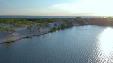 Aerial-shot-over-the-sand-dunes-and-the-Ontario-lake-at-sunset