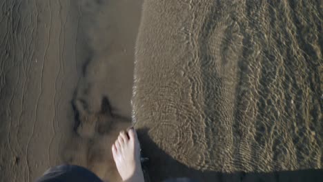 Top-view-of-female-legs-walking-along-shoreline