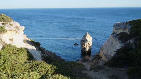 Einspielung,-Malerischer-Blick-Auf-Den-Weg,-Der-Zum-Rock-Tunnel-Beach-An-Der-Algarve,-Portugal,-Führt,-Ein-Boot,-Das-Im-Hintergrund-Auf-Dem-Meer-Vorbeifährt