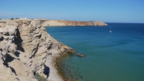 Einspielung,-Malerischer-Blick-Auf-Die-Felsige-Klippe-An-Der-Algarve,-Portugal,-Boot,-Das-An-Einem-Hellen,-Sonnigen-Tag-Im-Meer-Schwimmt