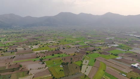 Picturesque-plateau-with-agricultural-fields,-mountains-in-background