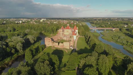 Aerial-flying-away-from-Bauska-castle-in-Latvia-at-golden-hour,-showing-a-tourist-attraction