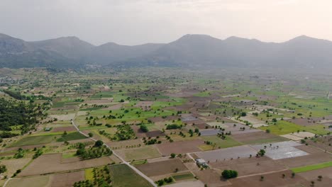 Aerial-over-beautiful-clean-green-valley-surrounded-by-tall-dense-mountains