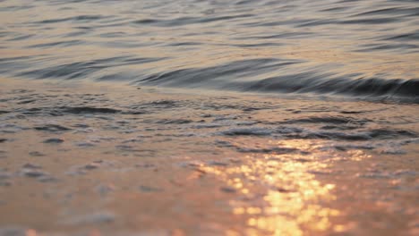 Schaumige-Wellen,-Die-Bei-Sonnenuntergang-Am-Ufer-Rollen,-Schmale-Sicht