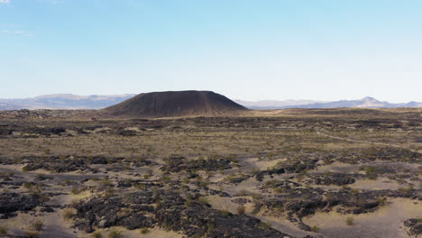 Low-altitude-aerial-view-approaching-volcanic-Amboy-Crater-in-the-Mojave-Desert