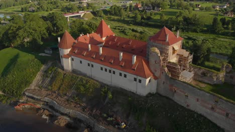 Slow-aerial-over-Bauska-castle-reconstruction-and-ruins-with-scaffolding-in-Latvia