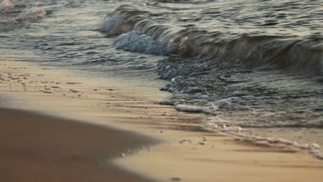 Waves-rolling-on-sandy,-golden-shore-at-the-sunset,-narrow-view
