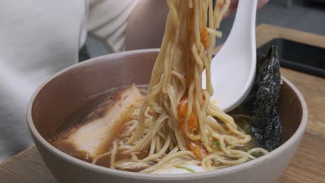 Woman-stiring-up-a-ramen-noodle-soup-with-chopsticks
