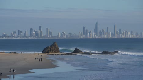 Surfers-In-Currumbin-Beach---View-Of-Gold-Coast-Skyline-In-The-Background---Queensland,-Australia---wide-shot
