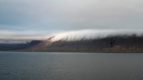Mountains-under-cloud-cover-from-Icelandic-bay,-long-shot