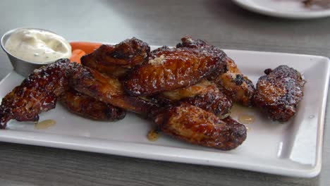 person-eating-glazed-chicken-wings-at-a-restaurant