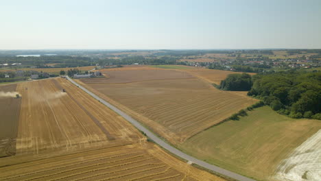 Die-Wunderbare-Weite-Plantage-In-Kielno-Polen-Mit-Landmaschinen,-Die-Unter-Dem-Strahlend-Blauen-Himmel-Ernten---Luftaufnahme