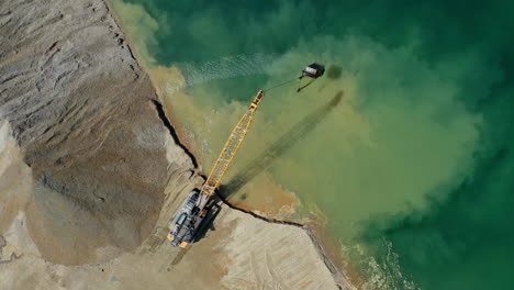 Aerial-top-down-view-of-an-excavator-moving-crushed-stone-into-the-water