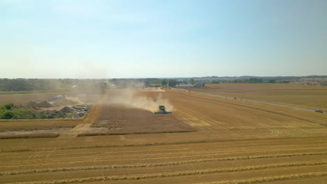 Combine-Harvester-Works-the-Farm-in-a-Golden,-Dusty-Field-on-a-Sunny-Day,-Drone-Aerial