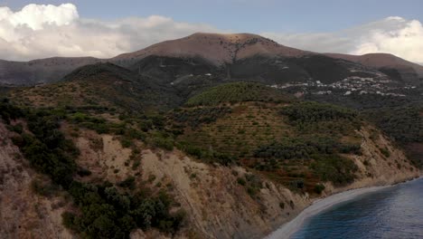 Hermosa-Playa-Con-Pueblos-De-Montaña-Sobre-Agua-De-Mar-Azul-Turquesa-Cerca-De-Saranda,-Albania