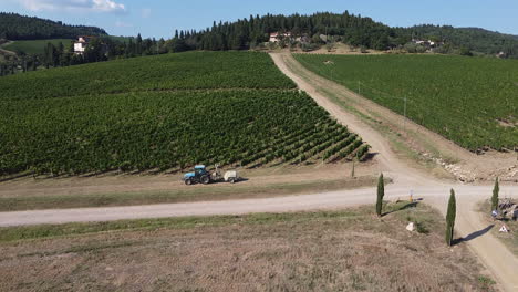 Agricultural-tractor-between-green-hills-and-vineyards-Tuscany-province,-Italian-countryside