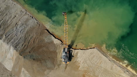 Aerial-view-of-excavator-moving-sand-and-gravel-on-the-lakeside,-heavy-industry-and-construction-equipment
