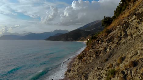 Playa-Panorámica-Con-Colinas-Rocosas-En-La-Costa-Bañada-Por-Las-Olas-Del-Mar-En-Un-Día-Nublado-En-El-Mediterráneo