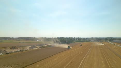 Dust-From-A-Farm-Tractor-Harvesting-Crops-In-The-Agricultural-Field-In-Kielno,-Poland---descending-drone-shot