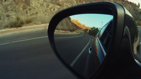 Car-side-mirror-during-a-daytime-trip