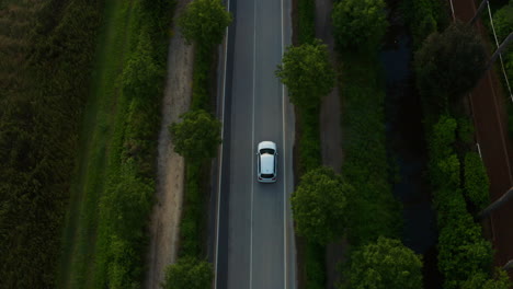 Car-driving-down-empty-road-in-Italy-countryside,-Aerial-Top-Down-View