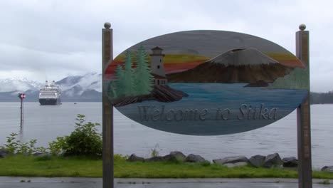 Welcome-to-Sitka,-Alaska-sign-from-the-touristic-dock-and-a-cruise-ship-in-the-background