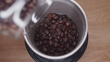 Coffee-beans-pour-out-from-glass-jar-into-coffee-grinder-machine