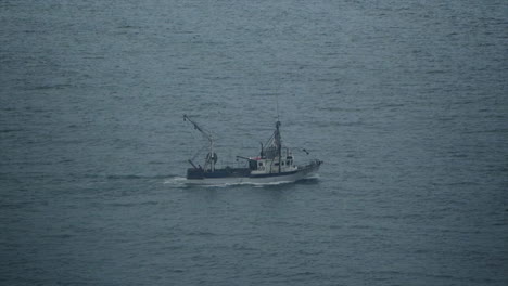A-Fishing-Trawler-Boat-Drags-it's-net-in-Slow-Motion-through-Calm-Cold-Ocean-Waters-on-a-Cold-Wintery-Morning