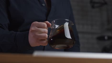 Man-shakes-a-glass-pot-with-coffee-inside