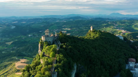 San-Marino-sunrise,-Aerial-flying-over-cliff-fortresses