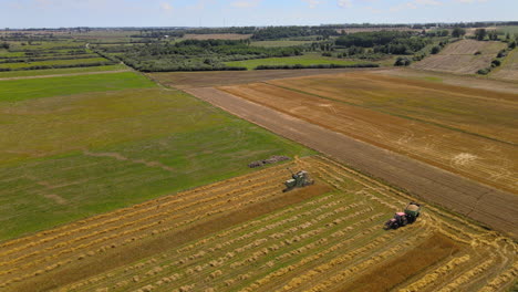 Aerial-dolly-forward-over-tractors-harvesting-crops-from-scenic-agricultural-farm-field