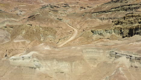 Rotierende-Drohnenansicht,-Die-Eine-Unbefestigte-Straße-Zeigt,-Die-Sich-Durch-Die-Geologischen-Formationen-Im-Regenbogenbecken-In-Der-Mojave-Wüste-Schlängelt