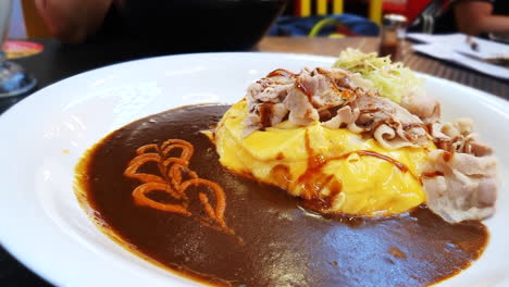 Japanese-curry-with-pork-bacon-and-egg-omelette-on-top-of-Japanese-rice-in-cosy-restaurant