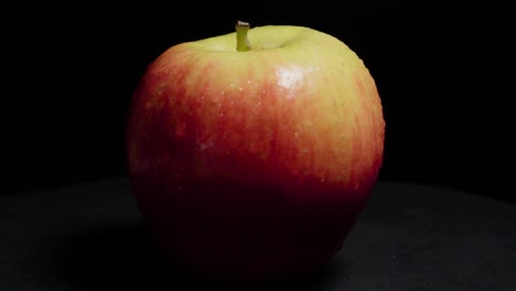 Rotating-Fuji-Apple-with-Water-Droplets-on-Isolated-Black-Background,-Closeup