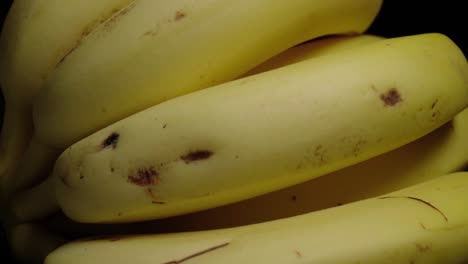 Tilt-Down-of-Bananas-Isolated-on-Black-Background,-Closeup