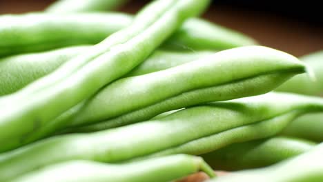 Raw-fresh-uncooked-string-beans-on-wooden-kitchen-surface-close-up-selective-focus-dolly-left