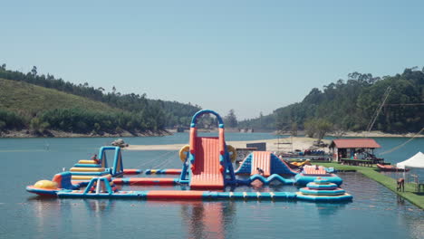 People-Enjoying-On-The-Inflatable-Outdoor-Water-Park-In-Vieira-Do-Minho,-Portugal-During-Summertime---wide-shot