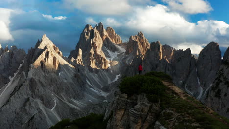 Man-in-red-jacket-standing-on-cliff-overlook-at-Dolomites
