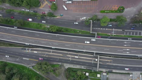 Tracking-aerial-flight-directly-above-traffic-and-white-car-speeding-and-traveling-on-Mexico-City-Periferico-Sur-expressway,-Mexico,-overhead-drone-sideways