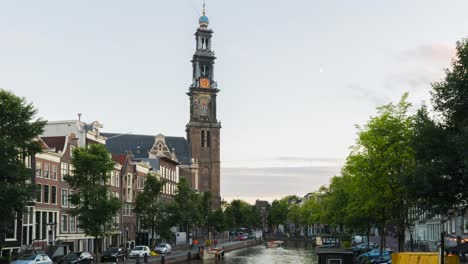 A-wide-day-to-night-timelapse-of-a-cityscape-on-the-Prinsengracht-with-Anne-Frank's-house-and-the-Westerkerk-church-in-Amsterdam,-in-summertime-with-some-clouds