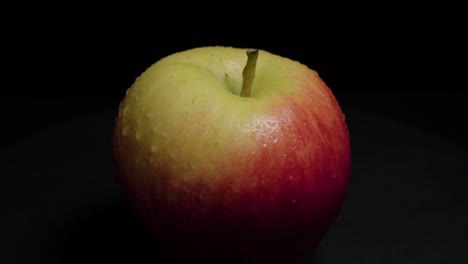 Apple-with-Water-Drops-on-Black-Background,-Closeup-Tilt-Down
